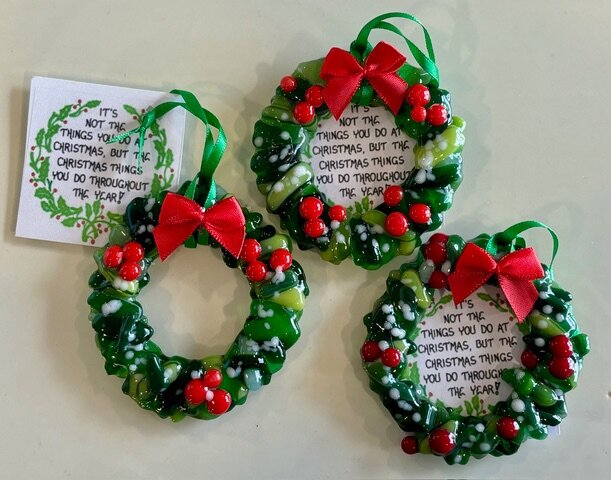 Lead image of the Ornaments room: green fused-glass wreath ornaments with red berries and red bows.