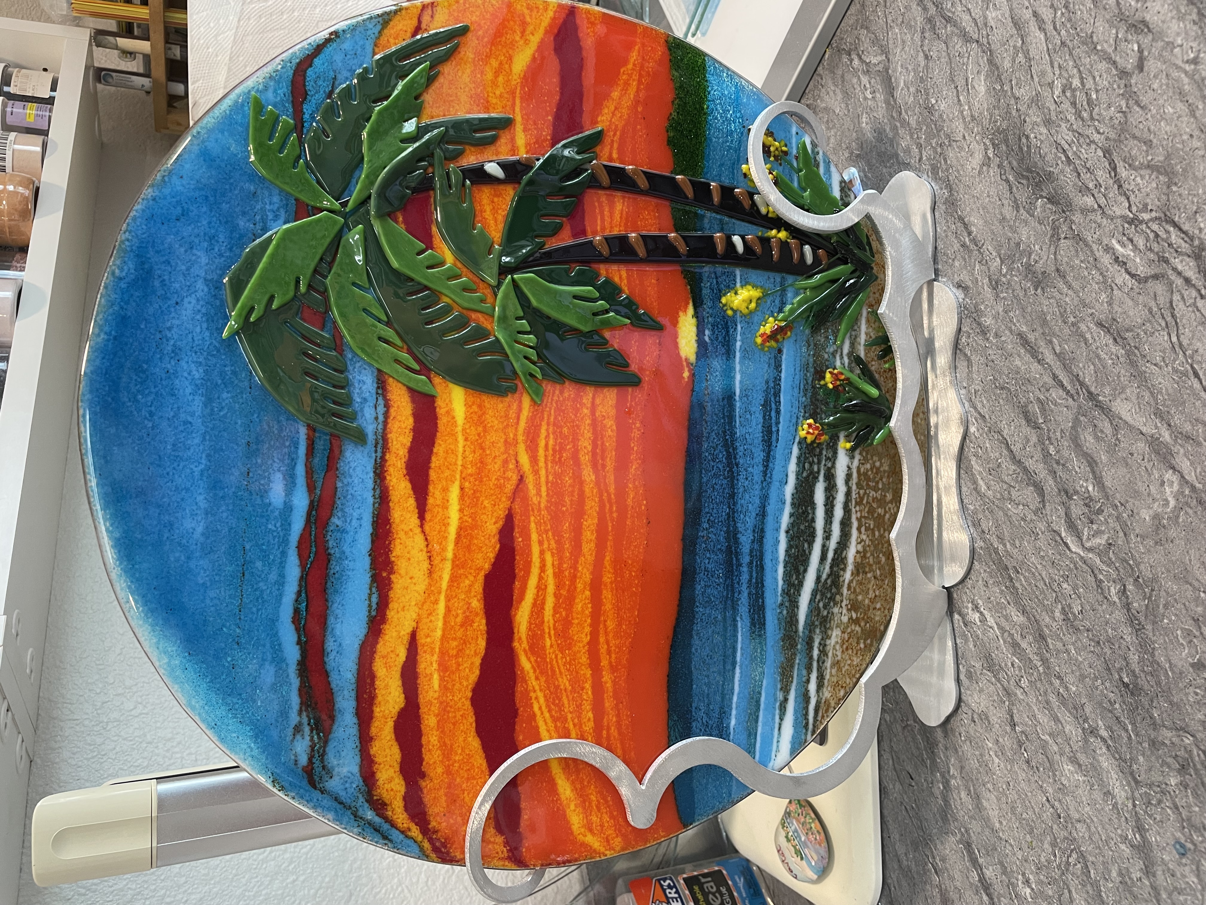 A warm-toned fused-glass platter with palm motif.